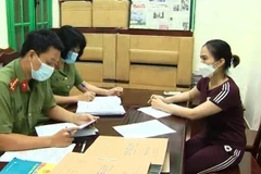 Đối tượng Hoàng Thị Thanh Nga làm việc với cơ quan điều tra. (Ảnh: TTXVN phát)