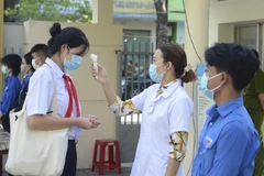 Học sinh được đo thân nhiệt, rửa tay bằng nước sát khuẩn trước khi vào phòng thi. (Ảnh: Văn Dũng/TTXVN) 