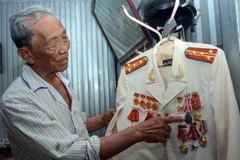 Đại tá Bành Văn Đởm bên những huân, huy chương được tặng thưởng. (Ảnh: TTXVN phát)