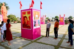 Người dân xem triển lãm tranh cổ động kỷ niệm 110 năm Ngày Bác Hồ ra đi tìm đường cứu nước tại khuôn viên Bảo tàng Hồ Chí Minh chi nhánh Bình Thuận. (Ảnh: Nguyễn Thanh/TTXVN)