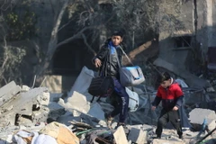 Người dân nhặt nhạnh đồ đạc còn sót lại trong đống đổ nát sau vụ không kích của Israel xuống trại tị nạn Al-Maghazi ở Dải Gaza ngày 31/12/2023. (Ảnh: THX/TTXVN)