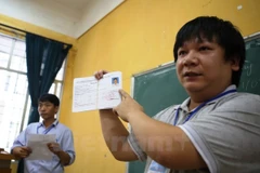 Cán bộ coi thi hướng dẫn thi sính về thủ tục dự thi. (Ảnh: Lê Minh Sơn/Vietnam+)