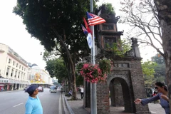 Cờ Mỹ, cờ Triều Tiên và cờ Việt Nam, bên dưới là biểu tượng hai bàn tay bắt chặt vào nhau thể hiện tinh thần của cuộc gặp lớn, được treo quanh hồ Hoàn Kiếm. (Ảnh: Danh Lam/TTXVN)