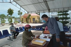 Đo thân nhiệt người bán vé số, người lao động tự do đến nhận hỗ trợ. (Ảnh minh họa. Nguồn: TTXVN)