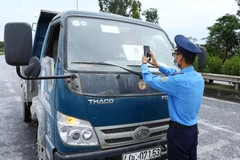 Lực lượng chức năng quét mã QR của phương tiện tham gia giao thông tại chốt kiểm soát dịch ngã 3 Cầu Giẽ, huyện Phú Xuyên hướng từ Hà Nam về Hà Nội trên tuyến Quốc lộ 1A. (Ảnh: Phạm Kiên/TTXVN)