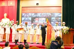 Chủ tịch nước Nguyễn Xuân Phúc gắn Huân chương Bảo vệ Tổ quốc hạng Nhất lên lá cờ truyền thống của lực lượng an ninh nhân dân. (Ảnh: Phạm Kiên/TTXVN)