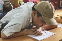 Anh Phùng Văn Trường viết chữ bằng miệng. (Ảnh: PV/Vietnam+)