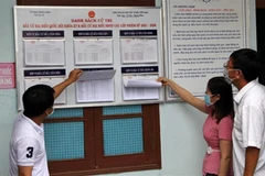 Người dân xem danh sách niêm yết cử tri. (Ảnh minh họa. Nguồn: TTXVN)