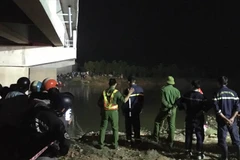 Lực lượng chức năng tìm kiếm nam học sinh bị rơi xuống sông. (Nguồn: Lao Động)