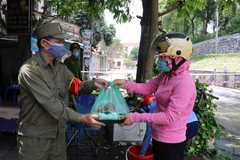 Phụ nữ phường Vũ Ninh, thành phố Bắc Ninh trao các suất cơm tình nguyện cho các tình nguyện viên chốt tại chốt kiểm soát dịch COVID-19 tại địa bàn phường Vũ Ninh, thành phố Bắc Ninh. (Ảnh: Thanh Thương/TTXVN)