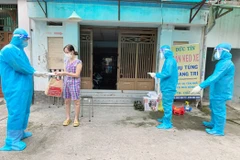 Nhân viên y tế trạm y tế lưu động phường 25, quận Bình Thạnh phát túi thuốc cho F0 điều trị tại nhà. (Ảnh: Đinh Hằng/TTXVN)
