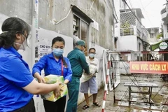  Tình nguyện viên, đoàn viên thanh niên Thành phố Hồ Chí Minh vận chuyển thực phẩm, nhu yếu phẩm để gửi đến người dân tại một khu vực cách ly tại quận Tân Phú. (Ảnh: Hồng Giang/TTXVN)