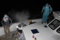 Lực lượng chức năng phun thuốc khử trùng cho nhóm người nhập cảnh trái phép. (Nguồn: Dân Trí)