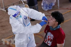 Bác sỹ lấy mẫu xét nghiệm cho một người dân ở Vientiane. (Ảnh: Phạm Kiên/TTXVN)