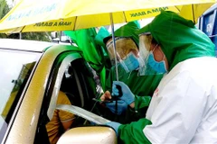  Lực lượng tình nguyện viên kiểm tra giấy xét nghiệm SARS-CoV-2 xe vào địa phận thành phố Cần Thơ. (Ảnh: Thu Hiền/TTXVN)