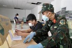 Cán bộ, chiến sỹ hỗ trợ các em học trực tuyến tại lớp học dã chiến ở chung cư 1050 (quận Bình Thạnh). (Ảnh: Thu Hương/TTXVN)