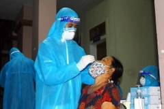 Cán bộ y tế lấy mẫu xét nghiệm cho người dân xã Hưng Đông, thành phố Vinh (Nghệ An) vào tối 20/6. (Ảnh: Tá Chuyên/TTXVN)