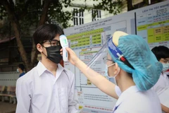 Kiểm tra thân nhiệt các thí sinh dự thi tại điểm thi Trường Trung học phổ thông Ngô Sỹ Liên, Bắc Giang. (Ảnh: Danh Lam/TTXVN)