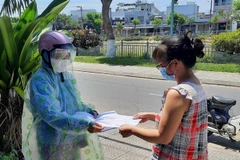 Đại diện chính quyền địa phương phát Thẻ đi chợ đến tận nhà cho các hộ dân quận Thanh Khê (Đà Nẵng). (Ảnh: TTXVN phát)