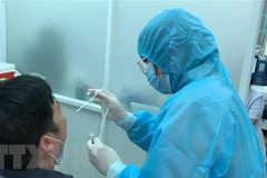 Nhân viên Trung tâm Y tế quận 3 lấy mẫu xét nghiệm cho người dân. (Ảnh: Đinh Hằng/TTXVN)