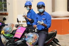 Đội hình 'shipper áo xanh' phường 11, thành phố Cao Lãnh, tỉnh Đồng Tháp được trang bị khẩu trang, kính chống giọt bắn, bao tay để đảm bảo an toàn cho cá nhân và cộng đồng. Ảnh: Chương Đài/TTXVN)