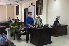 Bị cáo Vũ Đình Kiên (áo xanh, bên trái) và bị cáo Phạm Văn Úy và tại phiên tòa. (Ảnh: TTXVN phát)