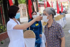 Các cử tri trước khi vào bầu cử được thực hiện khai báo y tế và đo thân nhiệt. (Ảnh: TTXVN)