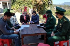 Cán bộ, chiến sỹ biên phòng tuyên truyền, vận động người dân ký cam kết tham gia tố giác người xuất nhập cảnh trái phép. (Ảnh: Đức Hiếu/TTXVN)
