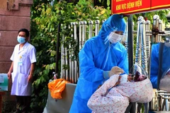 Người dân chờ được xét nghiệm nhanh trước khi vào khám, điều trị tại bệnh viện. (Ảnh: Công Tường/TTXVN)