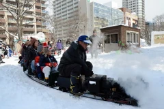Khách tham quan đi trên một mô hình đầu máy hơi nước tại Lễ hội Tuyết. (Nguồn: AFP/TTXVN)