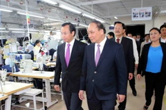Phó Thủ tướng Nguyễn Xuân Phúc thăm phân xưởng may của Công ty. (Ảnh: Trần Lê Lâm/TTXVN)
