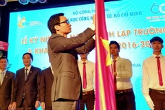 Phó Thủ tướng Vũ Đức Đam gắn Huân chương Độc lập Hạng Ba lên cờ truyền thống của Trường Đại học Công nghiệp Thành phố Hồ Chí Minh. (Ảnh: Thế Anh/TTXVN)