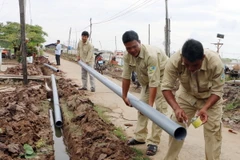 Lắp đặt ống cấp nước cho người dân vùng hạn mặn. (Ảnh: Hoài Thu/TTXVN)