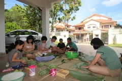 Cháu Nguyễn Như Phú (áo trắng, thứ tư từ trái sang) hoàn thành chiếc bánh chưng tự gói đầu tiên. (Ảnh: Hà Ngọc-Hoàng Nhương/Vietnam+)
