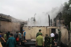 Các lực lượng chức năng tham gia ứng cứu, giúp đỡ các hộ gia đình bị cháy nhà ở thôn Mới, xã Xuân Giang, huyện Quang Bình. (Ảnh: Mộc Lan-TTXVN phát)