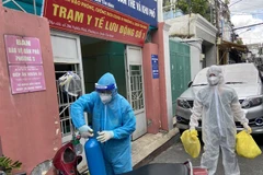 Lực lượng Quân y tại Trạm y tế lưu động số 1 (Phường 6, quận Tân Bình) mang các đồ dùng cần thiết (bình oxy, máy đo nồng độ oxy, ống nghe, nhiệt kế, dung dịch sát khuẩn, khẩu trang…) để đến nhà F0. (Ảnh: Mạnh Linh/TTXVN)