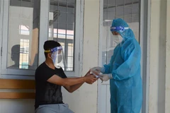 Cán bộ Trạm Y tế xã Bình Thành, huyện Thanh Bình, tỉnh Đồng Tháp đến kiểm tra sức khỏe và hướng dẫn sử dụng thuốc hỗ trợ điều trị COVID-19 cho đối tượng F0 đang điều trị tại nhà. (Ảnh: Nhựt An/TTXVN)