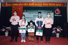 Lãnh đạo Ngân hàng Chính sách xã hội Chi nhánh tỉnh Sơn La ủn)g hộ máy tính cho các học sinh gia đình nghèo, có hoàn cảnh khó khăn. (Ảnh: Quang Quyết/TTXVN