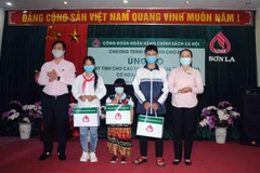 Lãnh đạo Ngân hàng Chính sách xã hội Chi nhánh tỉnh Sơn La ủn)g hộ máy tính cho các học sinh gia đình nghèo, có hoàn cảnh khó khăn. (Ảnh: Quang Quyết/TTXVN