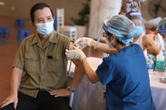 Nhân viên y tế vaccine phòng COVID-19 cho người dân tại điểm tiêm chủng quận Hoàn Kiếm (Hà Nội). (Ảnh: Minh Quyết/TTXVN)