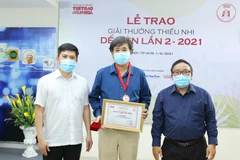 Ông Lê Xuân Thành, Trưởng Ban tổ chức Giải (trái) và nhà thơ Trần Đăng Khoa, Chủ tịch Hội đồng giám khảo (phải) trao giải cho tác giả Bình Ca (giữa). (Ảnh: Hòa Nguyễn/Vietnam+)