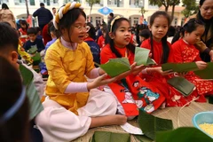 Các em nhỏ rất hào hứng khi được tham gia trải nghiệm gói bánh chưng đón Tết. (Ảnh: Huy Hùng/TTXVN)
