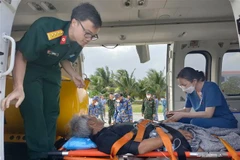 Bệnh nhân Huỳnh Bình được đưa lên trực thăng để chuyển vào bờ chữa trị. (Ảnh: TTXVN phát) 