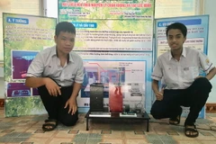 Hai em Lê Quang Minh và Phạm Nguyên Khang cùng sản phẩm Máy điều hòa theo nguyên lý chân không và tạo lốc xoáy. (Ảnh: Mai Trang/TTXVN)