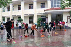Giáo viên, phụ huynh trường THCS Thạch Linh, thành phố Hà Tĩnh vệ sinh sân trường. (Ảnh: Công Tường/TTXVN)