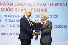 Chủ tịch Hội Hữu nghị Việt Nam-Romania Tống Văn Nga tặng hoa, chúc mừng 102 năm Quốc khánh Romania. (Ảnh: Văn Điệp - TTXVN)