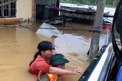 Lực lượng cứu nạn đưa người dân ra khỏi vùng lũ. (Ảnh: TTXVN)