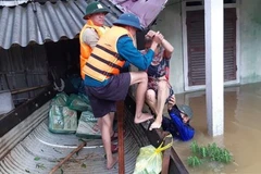 Lực lượng chức năng giúp người dân di dời đến nơi an toàn. (Ảnh: TTXVN phát)