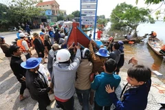  Các ngư dân chuyển thuyền đi biển xuống vùng lũ tại huyện Lệ Thủy hỗ trợ công tác cứu trợ đồng bào. (Ảnh: Thành Đạt/TTXVN)