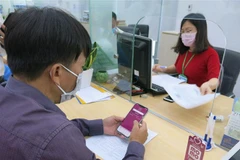 Người dân tham gia dịch vụ thanh toán không dùng tiền mặt khi giải quyết thủ tục hành chính tại Trung tâm Hành chính công tỉnh. (Ảnh: Chí Tưởng/TTXVN)